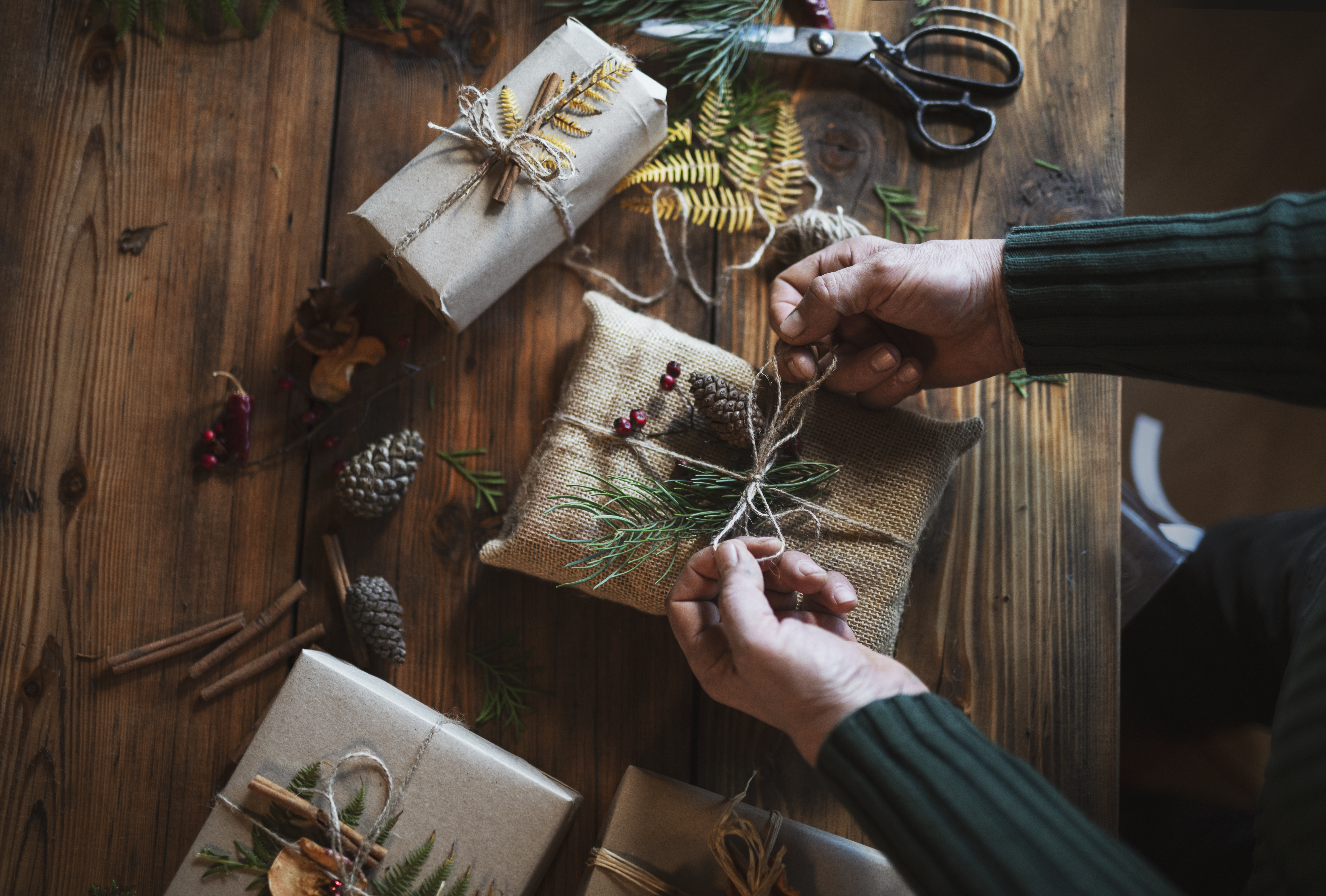 Händer som slår in julklappar på ett bord
