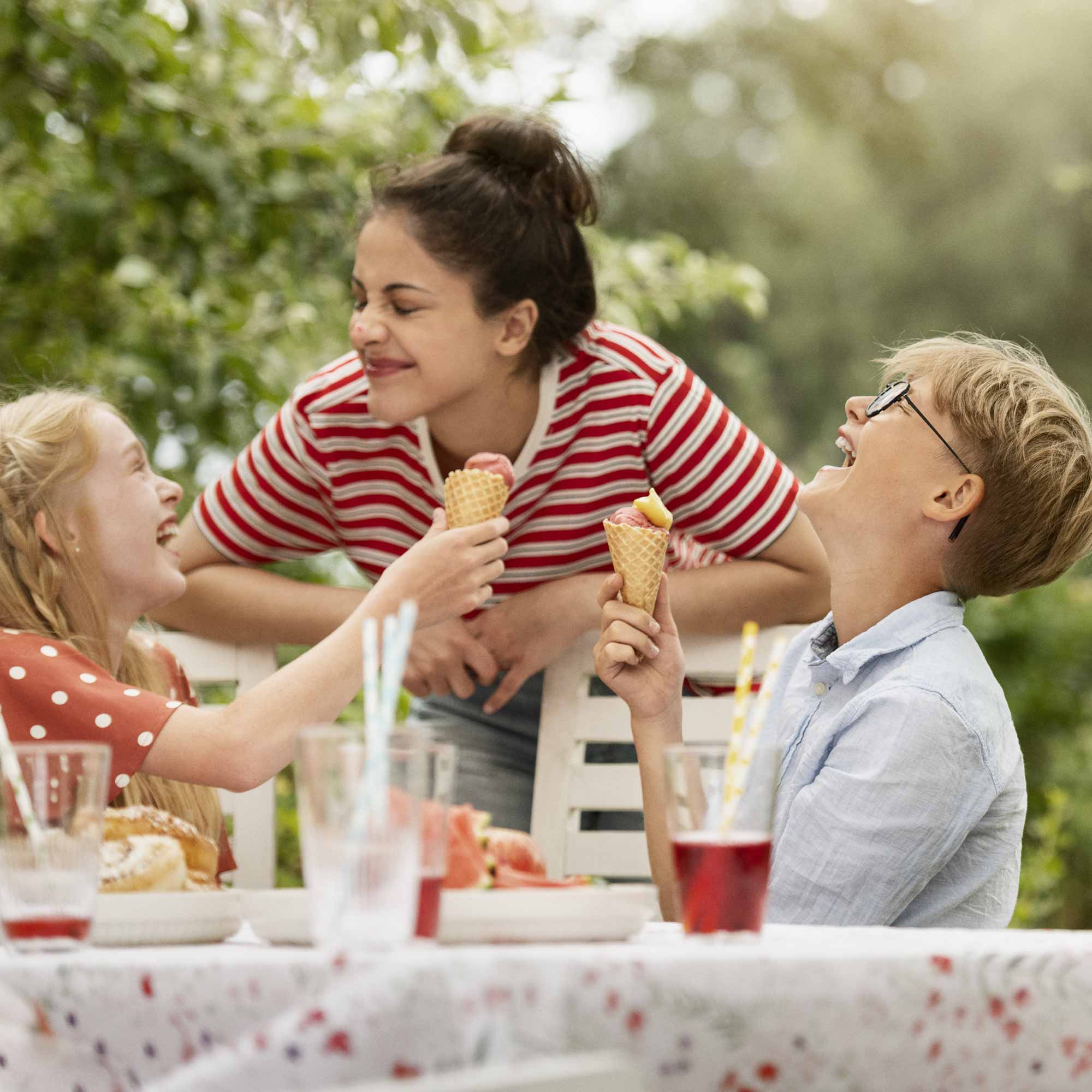 Kvinna och två barn äter glass ute i trädgården